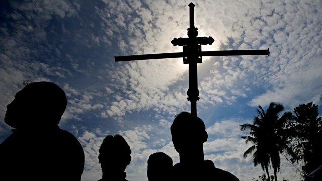 Seorang pria memegang salib dalam pemakaman massal para korban bom gereja, di sebuah pemakaman umum, Negombo, Sri Lanka. Foto: Reuters/Athit Perawongmetha