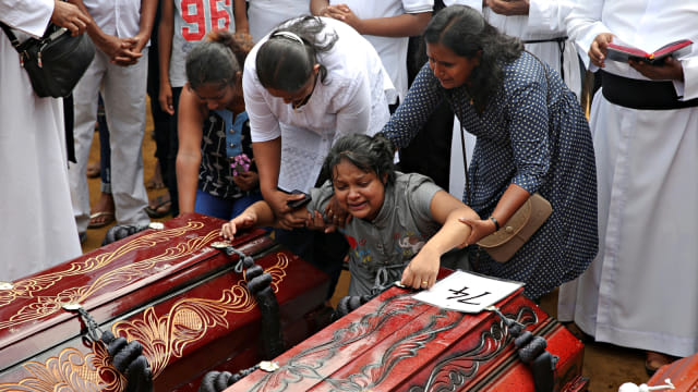 Seorang wanita tak kuasa menahan tangis saat keluarganya akan dimakamkan secara massal. Foto: Reuters/Athit Perawongmetha