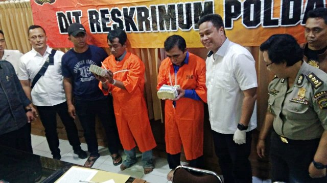 Tersangka modus penipuan memegang barang bukti saat konferensi pers. Foto: Dok. Polda Bali