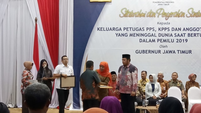 Gubernur Jawa Timur Khofifah Indar Parawansa dan Ketua KPU Choirul Anam memberi penghargaan untuk petugas pemilu yang meninggal dunia kepada perwakilan keluarga. Foto: Yuana Fatwalloh/kumparan