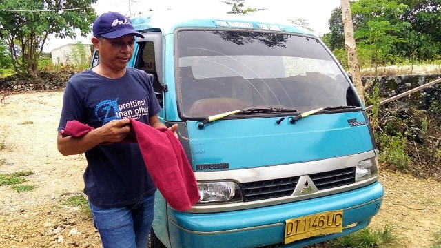 La Ode Alim disamping angkot pribadinya, Senin (29/04). Foto: Istimewa.