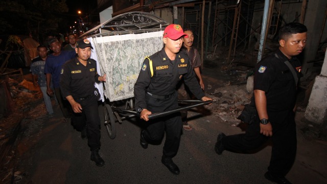 Petugas mengantar jenazah Sunaryo (58) untuk dimakamkan di Tempat Pemakaman Umum Rangkah, Surabaya, Jawa Timur, Rabu (24/4). Foto: ANTARA FOTO/Didik Suhartono