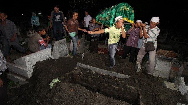 Warga memakamkan jenazah Sunaryo (58) di Tempat Pemakaman Umum Rangkah, Surabaya, Jawa Timur, Rabu (24/4). Foto: ANTARA FOTO/Didik Suhartono