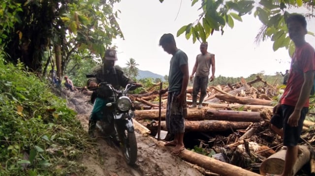 Pengendara motor saat melintasi jalan alternatif di lokasi perkebunan warga pasca banjir bandang di Desa Tuva, Kecamatan Dolo Selatan, Kabupaten Sigi, Sulteng, Selasa (30/4). Foto. Jems