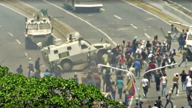 Kendaraan Pengawal Nasional Venezuela (GNB) membubarkan demonstran oposisi di jalan Caracas. Foto: REUTERS / Juan Carlos Ulate