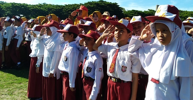 Siswa-siswi sekolah dasar memberi hormat kepada bendera merah putih dalam upacara peringatan Hari Pendidikan Nasional di Lapangan Blang Padang, Banda Aceh, Kamis (2/5). Foto: Husaini/acehkini