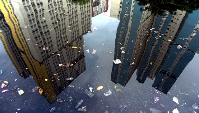 Refleksi gedung bertingkat dari Kali Item, Sunter, Jakarta  Utara, yang dipenuhi sampah plastik. Foto: Jamal Ramadhan/kumparan