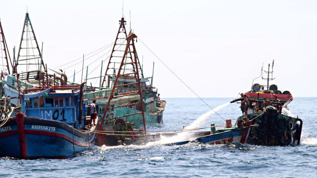 Sejumlah anak buah kapal bantu menyemprotkan air menggunakan mesin pompa ke dalam kapal nelayan Vietnam. Foto: Antara/Jessica Helena Wuysang