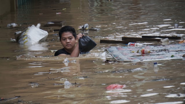 Seorang warga menerobos banjir di Kalibata. Foto: Jamal Ramadhan/kumparan