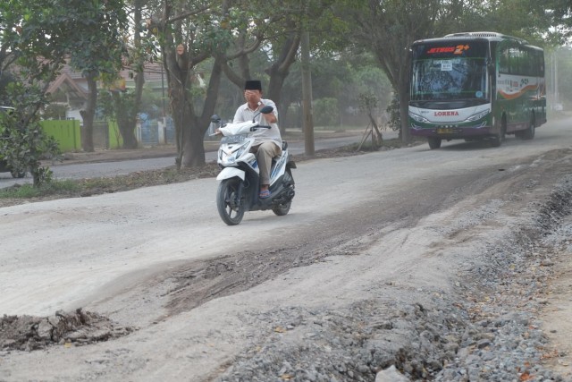 Seorang pengedara motor menutup mata lantaran banyaknya debu yang berterbangan di Jalan Mayjend Ryacudu, Selasa (7/5) | Foto : Obbie Fernando/Lampung Geh