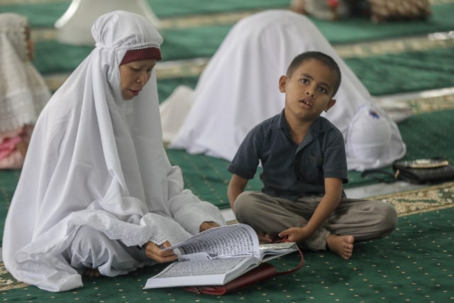 Seorang ibu membaca Alquran di Masjid Raya Baiturrahman, Banda Aceh, Rabu pagi (8/5) bertepatan hari ketiga puasa Ramadan 1440 hijriah. Foto: Suparta/acehkini