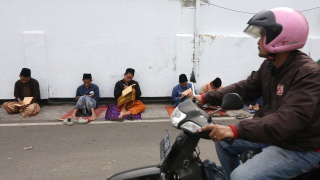 Sejumlah santri mengaji kitab kuning (kitab klasik berbahasa arab gundul) di pinggir jalan kompleks pondok pesantren Lirboyo, Kota Kediri, Jawa Timur, Kamis (9/5/2019). Foto: ANTARA FOTO/Prasetia Fauzani