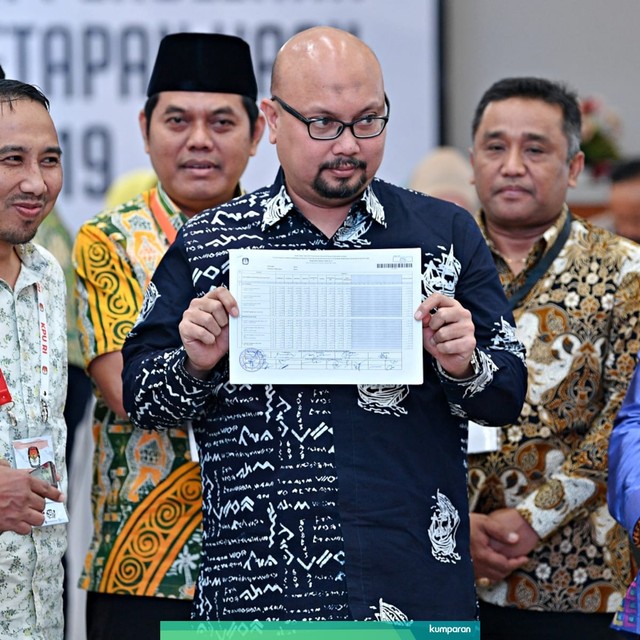 Komisioner KPU Ilham Saputra beserta sejumlah saksi menunjukkan berkas rekapitulasi Provinsi Bali. Foto: Antara/Sigid Kurniawan