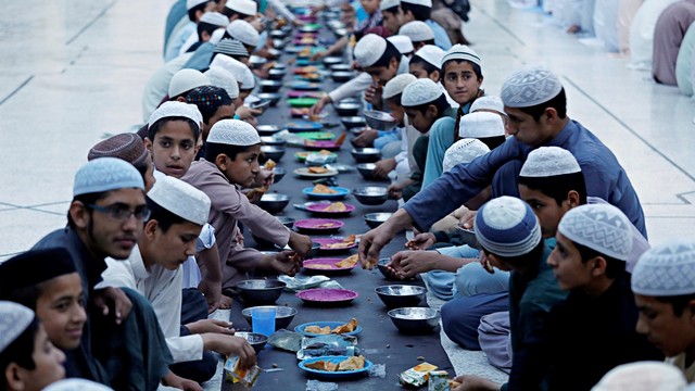 Umat Muslim di Pakistan sedang menyantap hidangan bersama saat berbuka puasa. Foto: Reuters/Fayaz Aziz