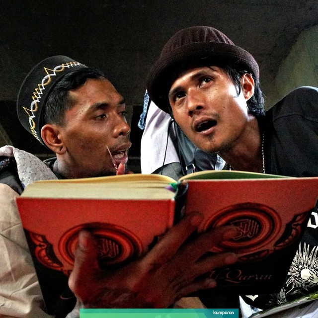 Dua orang pria sedang membaca kitab Al-Quran dalam kegiatan ngepunkburit di kolong fly over Tebet, Jakarta, Sabtu (11/5/2019). Foto: Nugroho Sejati/kumparan