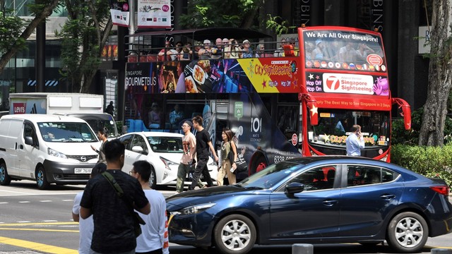 Sejumlah wisatawan saat menaiki bus Singapura. Foto: AFP/ROSLAN RAHMAN