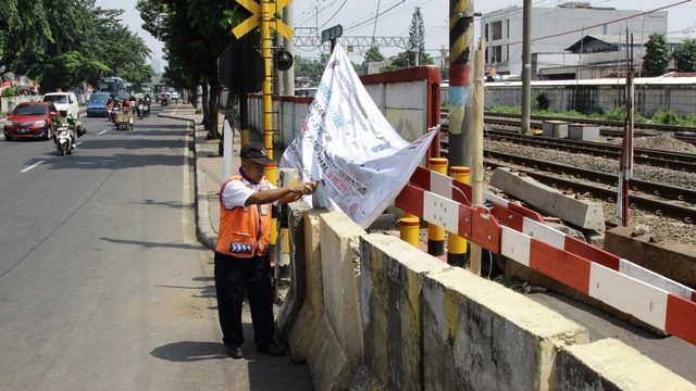 Petugas pintu kereta di lokasi rel kereta api Cipinang, Jakarta Timur yang ditutup karena pengoperasian lintasan kereta api Double-double Track (DDT). Foto: Helmi Afandi Abdullah/kumparan