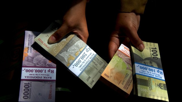Warga menunjukkan uang rupiah pecahan kecil di Lapangan Karebosi, Makassar, Sulawesi Selatan, Senin (13/5). Foto: ANTARA FOTO/Abriawan Abhe