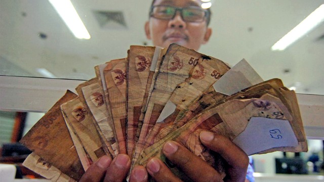 Petugas menunjukkan uang rusak saat penukaran di Kantor Perwakilan Bank Indonesia. Foto: ANTARA FOTO/Oky Lukmansyah