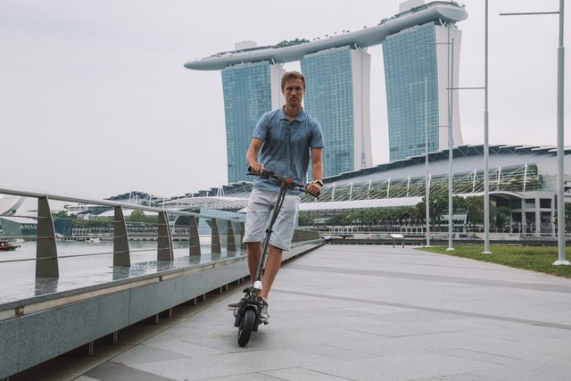 com-Mengendarai skuter di Singapura.
