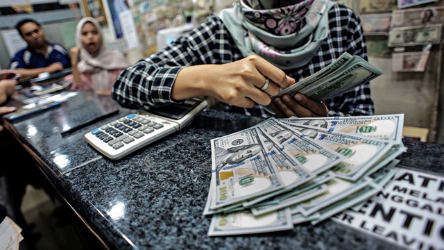 Seorang petugas menghitung mata uang dolar Amerika di salah satu gerai penukaran mata uang asing di Jakarta. Foto: Antara/Aprillio Akbar