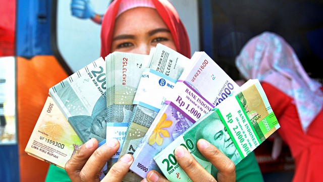 Warga menunjukkan uang pecahan rupiah. Foto: Antara/Arif Firmansyah