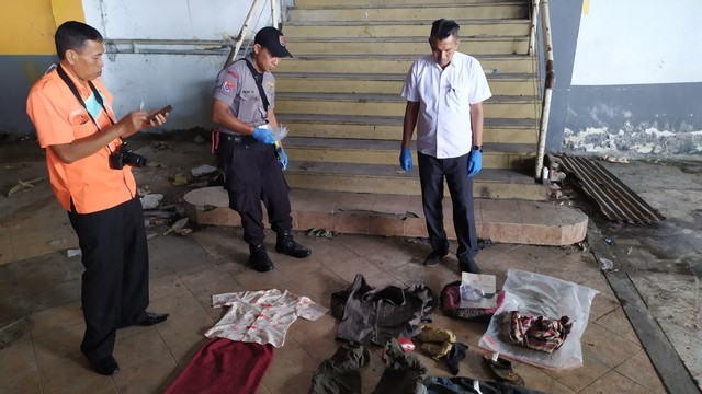 Tim kepolisian mengecek baju yang ditemukan di sekitar tempat kejadian perkara di lantai tiga Pasar Besar, Kota Malang. Baju-baju tersebut diduga milik korban. (Foto: Gigih mazda/tugu malang).