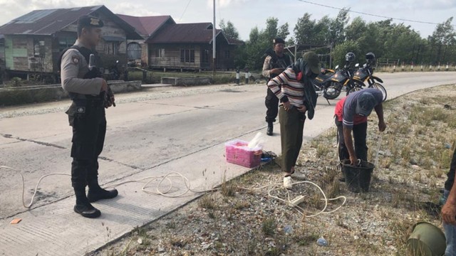 PENYIDIK KPK didampingi anggota Polres Bengkalis bersenjata laras panjang mendampingi proses pengecekan kualitas jalan di Bengkalis. 