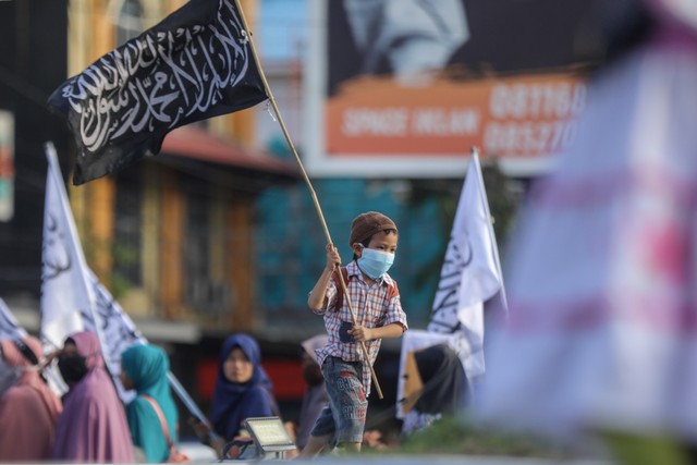 Seorang anak mengusung bendera tauhid di sela aksi solidaritas untuk Palestina di Bundaran Simpang Lima, Banda Aceh, Kamis (16/5). Foto: Suparta/acehkini 