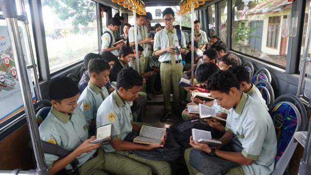 Siswa SMA Labschool Unsyiah membaca Alquran dalam Bus Trans Kutaraja dalam kegiatan 'Ngaji On Street' di bulan Ramadan. Foto: Dok. Rohis Labschool