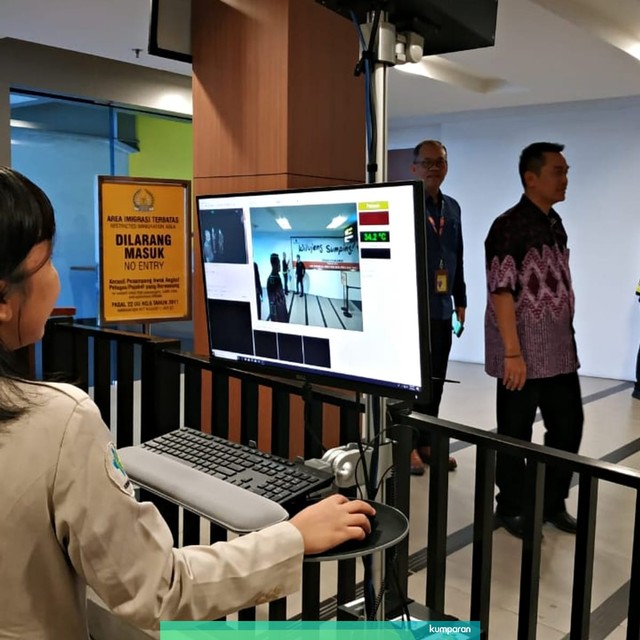 Seorang petugas sedang mengoperasikan alat pemindai suhu tubuh bernama thermo scanner di Bandara Internasional Husein Sastranegara, Bandung. Foto: Rachmadi Rasyad/kumparan
