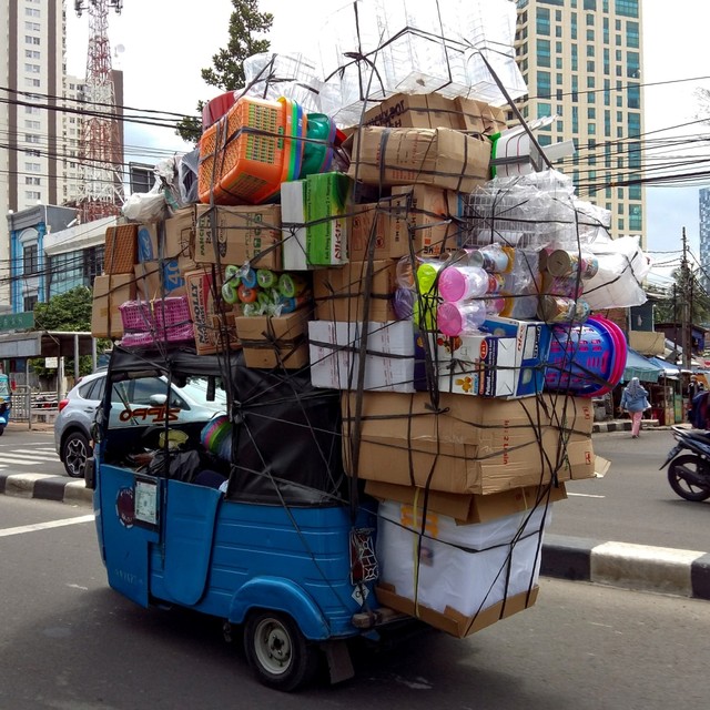 Sebuah bajaj dipenuhi barang penumpang saat melintas di jalanan Jakarta. Foto: AFP/BAY ISMOYO