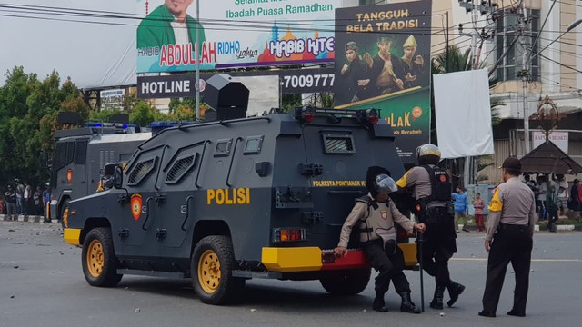 Petugas berjaga di perempatan Hotel Garuda, saat massa membakar pos polisi di kawasan itu. Foto: Daddy Cavalero