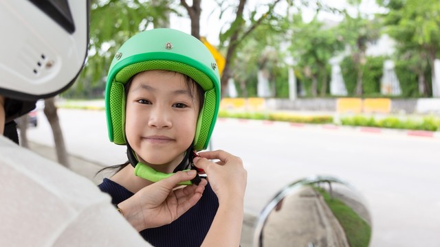 ibu memasang helm anak untuk naik motor Foto: Shutterstock