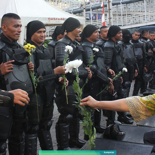 Seorang peserta dari Gerakan Nasional Kedaulatan Rakyat memberi setangkai bunga kepada personel polisi. Foto: ANTARA FOTO/Laily Rahmawaty