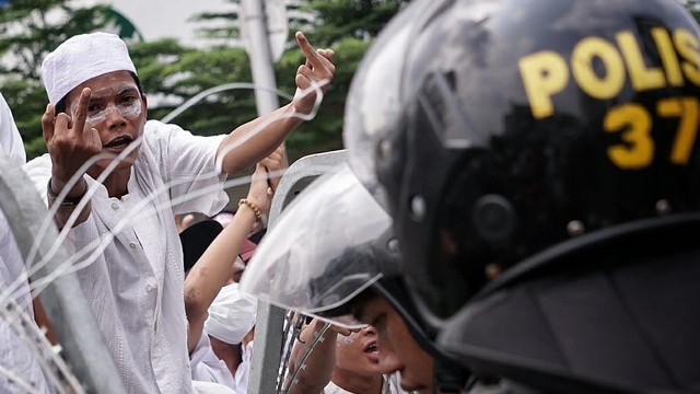 Seorang massa aksi unjuk rasa mengacungkan jari tengahnya. Foto: Jamal Ramadhan/kumparan