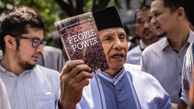 Dewan Pembina BPN Prabowo-Sandi, Amien Rais menunjukkan buku berjudul Jokowi People Power saat jeda pemeriksaan untuk Shalat Jumat di Direktorat Reserse Kriminal Umum Polda Metro Jaya, Jakarta, Jumat (24/5). Foto: ANTARA FOTO/Aprillio Akbar