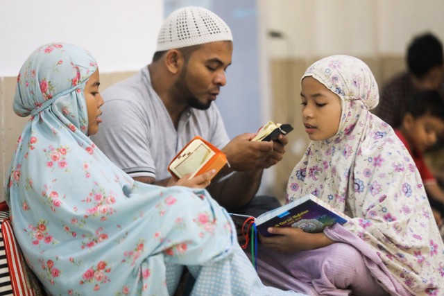 Warga bersama dua anaknya membaca Alquran di Masjid Oman, Banda Aceh. Foto: Suparta/acehkini