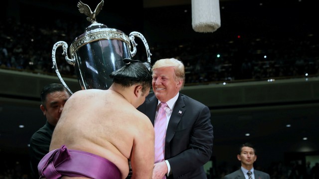 Presiden AS Donald Trump memberikan piala kepada pemenang Turnamen Sumo Musim Panas di Aula Sumo Ryogoku Kokigikan, Jepang. Foto: REUTERS/Jonathan Ernst
