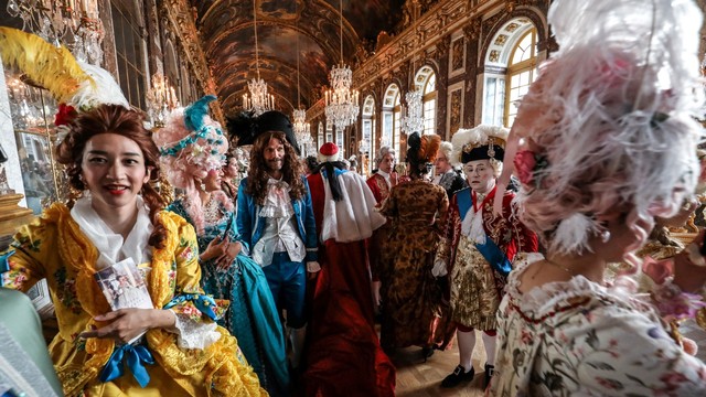 Orang-orang yang mengenakan kostum ala kerajaan Prancis di "galerie des glaces", Chateau de Versailles. Foto: AFP/Ludovic MARIN