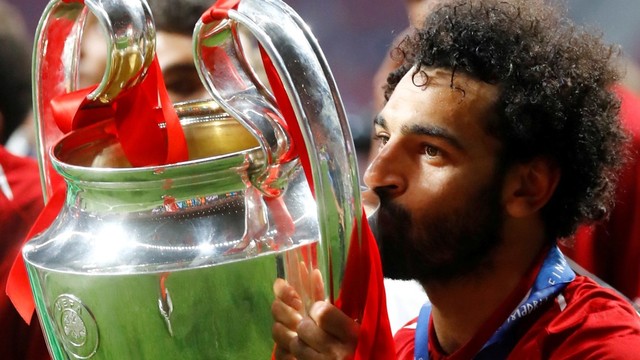 Mohamed Salah mencium trofi saat merayakan kemenangan Liga Champions. Foto: REUTERS/Kai Pfaffenbach