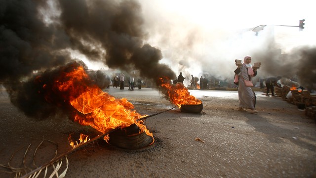 Demonstran Sudan saat memblokir jalan menggunakan batu dan membakar ban. Foto: AFP/ASHRAF SHAZLY