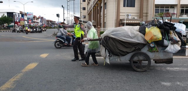 Ipda Fajar saat membantu seorang pemulung menyeberang jalan di persimpangan Hotel Garuda Pontianak. Foto: Dokumentasi Satlantas Polresta Pontianak