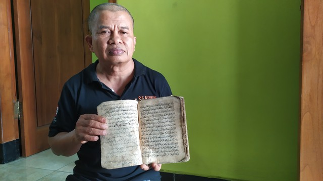 Lulut Edi Santoso, Guru SMA di Malang, dan salah satu naskah kuno koleksinya. (Foto: Gigih Mazda/Tugu Malang).