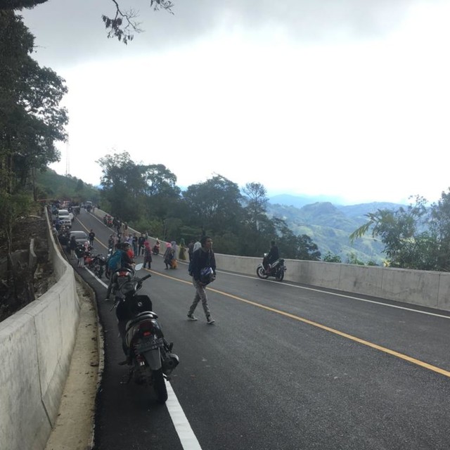 Warga yang melintas di jalan kawasan Bur Lintang berhenti untuk berfoto di jalan yang baru selesai diperbaiki dengan latar belakang pemandangan alam nan hijau. Foto: Windy/acehkini