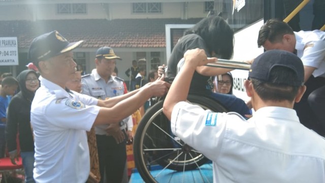 Petugas Dinas Perhubungan (Dishub) Kota Solo sedang membantu anak penyandang disabilitas untuk masuk ke bus yang akan memberangkatkan mereka pada kegiatan Mudik Ramah Anak dan Disabilitas Indonesia (MRADI). (Tara Wahyu N.V.)