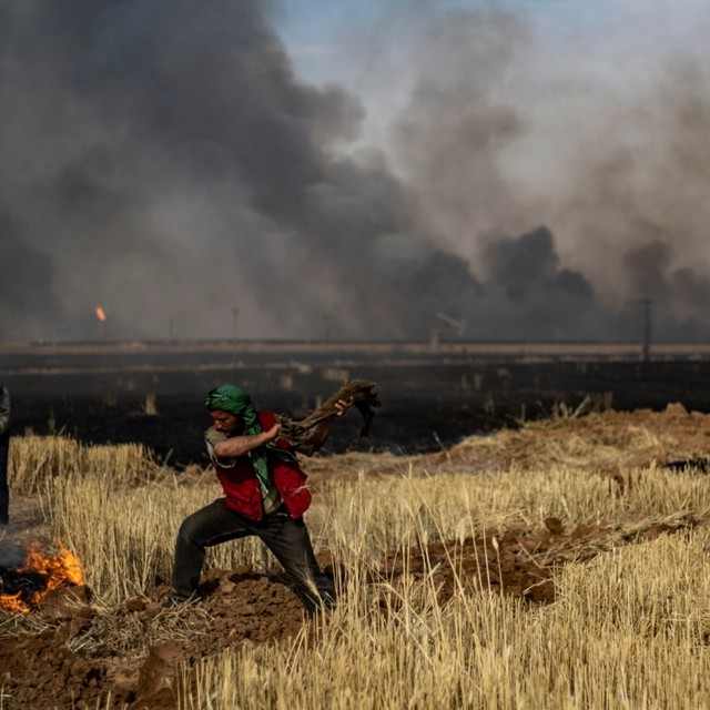 Para petani berupaya untuk memadamkan api yang berada di ladang gandumnya, Kurdi. Foto: AFP/DELIL SOULEIMAN