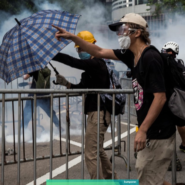 Para pengunjuk rasa melarikan diri saat polisi menembakkan gas air di luar Kompleks Dewan Legislatif, Hong Kong. Foto: AFP/ISAAC LAWRENCE
