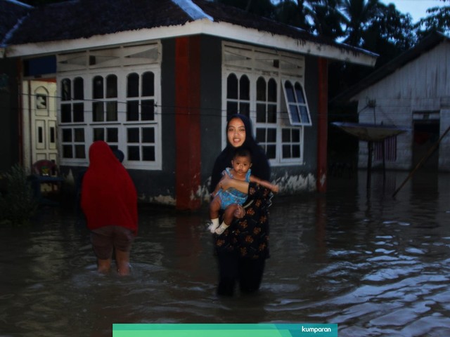 Seorang ibu membawa balitanya ke lokasi pengungsian saat banjir merendam di Desa Pondidaha, Kecamatan Pondidaha, Konawe, Sulawesi Tenggara, Rabu (12/6). Foto: ANTARA FOTO/Jojon