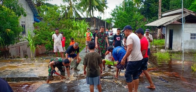 TNI AD Koramil Kumai bersama warga membongkar jalan untuk dijadikan drainase aliran gengan air yang membanjiri rumah warga. (Foto: Joko Hardyono)